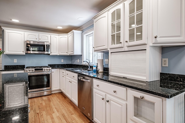 kitchen with white cabinets, appliances with stainless steel finishes, light wood-style flooring, and a sink