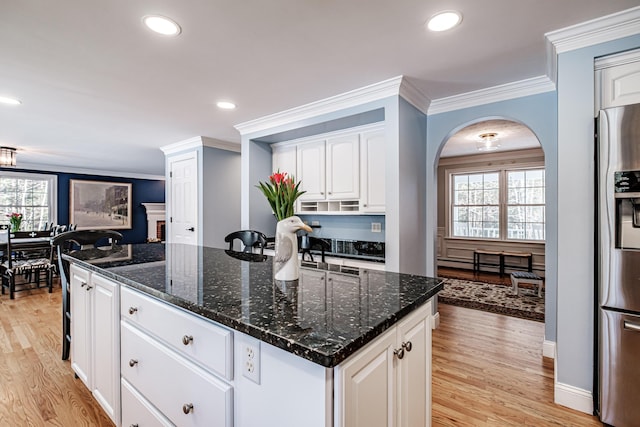 kitchen with arched walkways, stainless steel fridge, a wealth of natural light, and a kitchen island