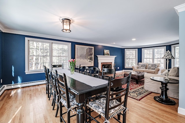 dining room featuring a brick fireplace, wood finished floors, baseboards, and ornamental molding