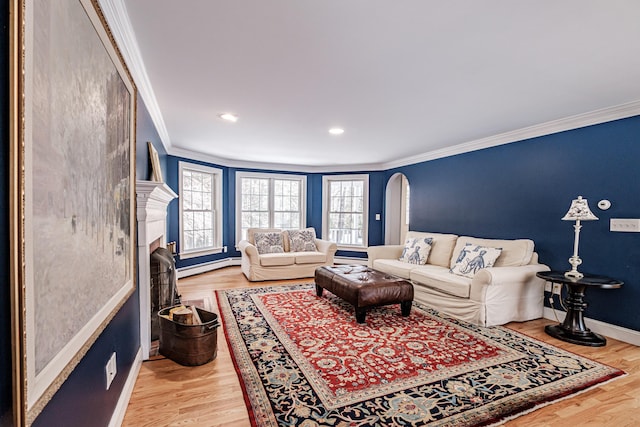 living area with a baseboard radiator, arched walkways, ornamental molding, and light wood-style flooring