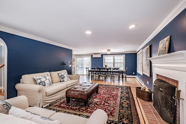 living room with crown molding, wood finished floors, arched walkways, and baseboard heating