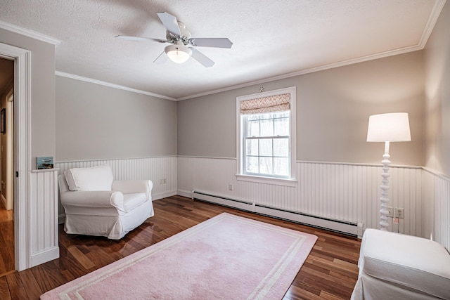 living area featuring wood finished floors, baseboard heating, and wainscoting