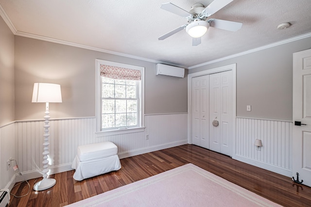 sitting room featuring ceiling fan, a wainscoted wall, a wall mounted air conditioner, baseboard heating, and wood finished floors