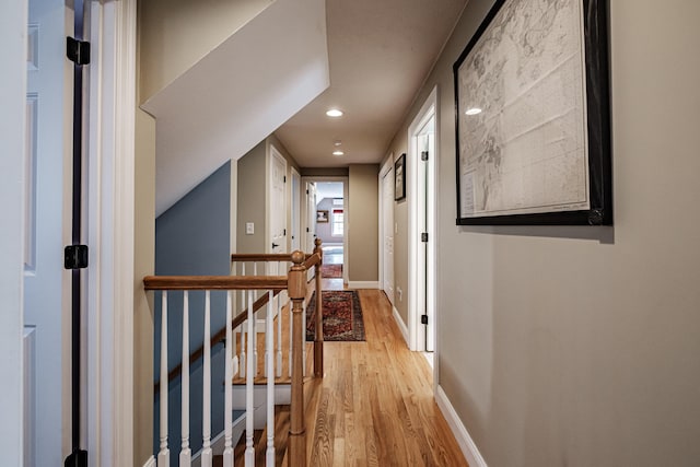 hallway with recessed lighting, an upstairs landing, baseboards, and light wood-type flooring