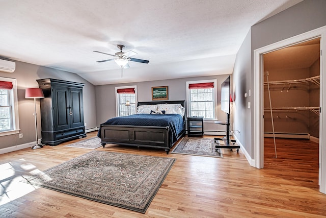 bedroom with lofted ceiling, light wood-style floors, baseboards, and a baseboard radiator