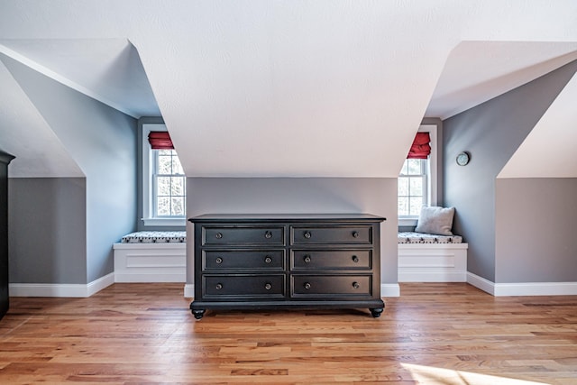 additional living space with vaulted ceiling, baseboards, light wood finished floors, and a textured ceiling