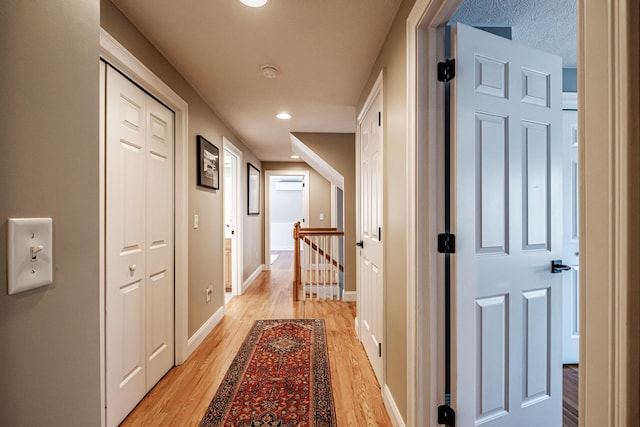 corridor with recessed lighting, an upstairs landing, light wood-style floors, and baseboards