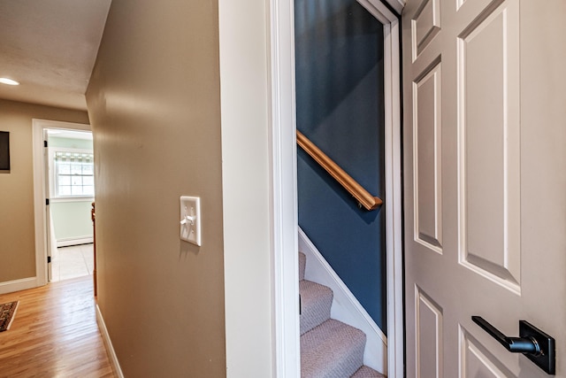 stairs with recessed lighting, a baseboard heating unit, baseboards, and wood finished floors