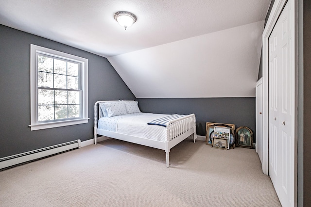 carpeted bedroom with a closet, baseboards, lofted ceiling, and a baseboard radiator