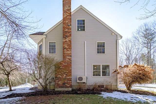 view of snowy exterior with ac unit and a chimney