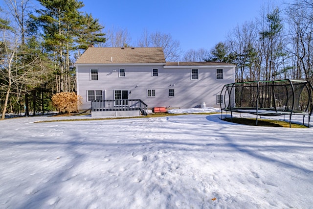 rear view of property featuring a deck and a trampoline