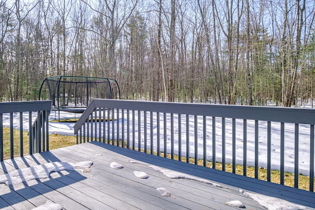 wooden terrace with a trampoline and a wooded view