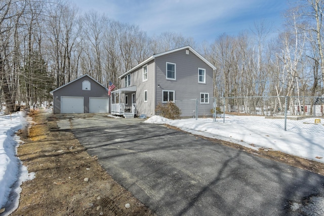 snow covered property featuring an outbuilding, a garage, and fence