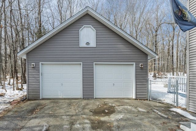 snow covered garage with a gate, fence, and a garage