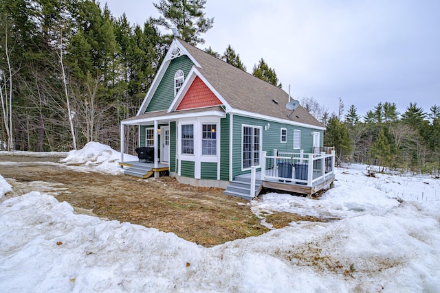 view of front of home featuring a deck and a shingled roof