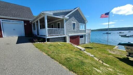 20 Wharf Rd, Blue Hill, ME 04614 - view of front facade featuring a water view, a porch, a front yard, a garage, and asphalt driveway