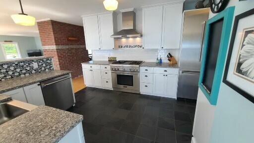 20 Wharf Rd, Blue Hill, ME 04614 - kitchen featuring wall chimney range hood, stainless steel appliances, white cabinets, and decorative backsplash