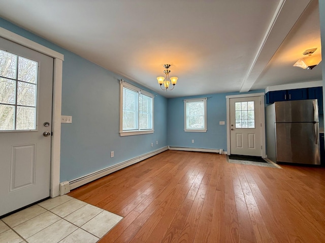 entrance foyer with a baseboard heating unit, baseboards, light wood finished floors, and a chandelier