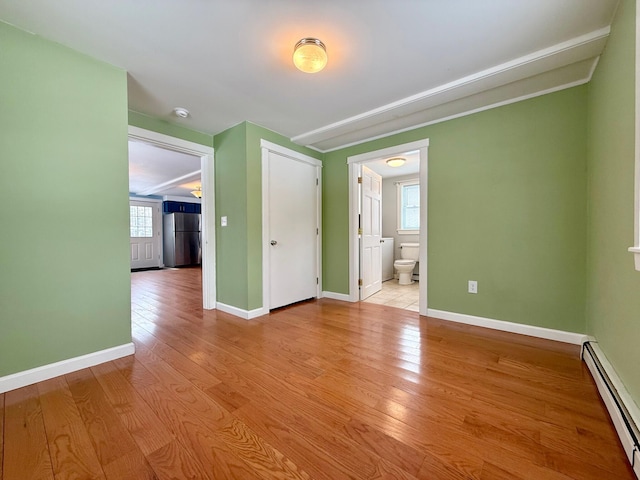 unfurnished room featuring a healthy amount of sunlight, light wood-style floors, baseboards, and a baseboard radiator