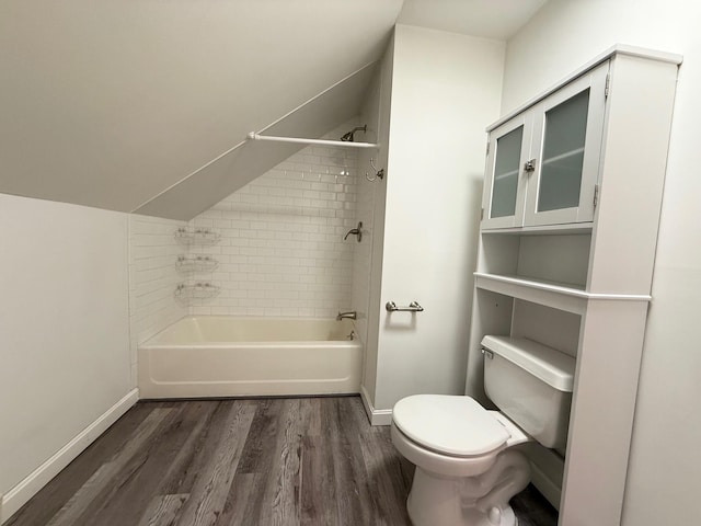 bathroom with toilet, wood finished floors, tub / shower combination, baseboards, and vaulted ceiling