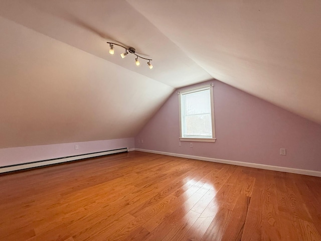 bonus room featuring vaulted ceiling, light wood-style floors, baseboards, and baseboard heating