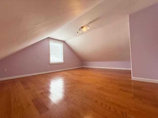 additional living space with lofted ceiling, baseboards, and light wood finished floors