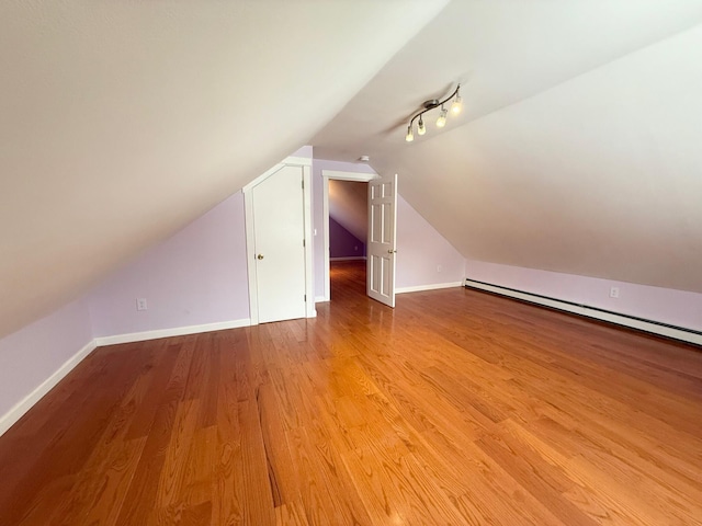 additional living space with baseboards, baseboard heating, lofted ceiling, and wood finished floors