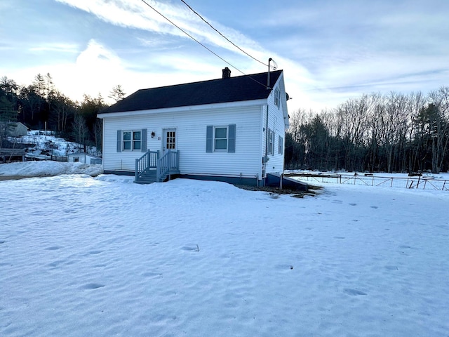 snow covered back of property featuring a chimney