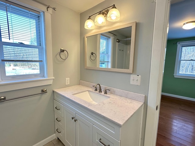 full bath featuring vanity, wood finished floors, and baseboards