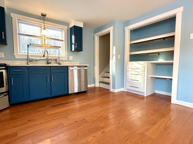 kitchen featuring blue cabinetry, light wood finished floors, appliances with stainless steel finishes, and a sink