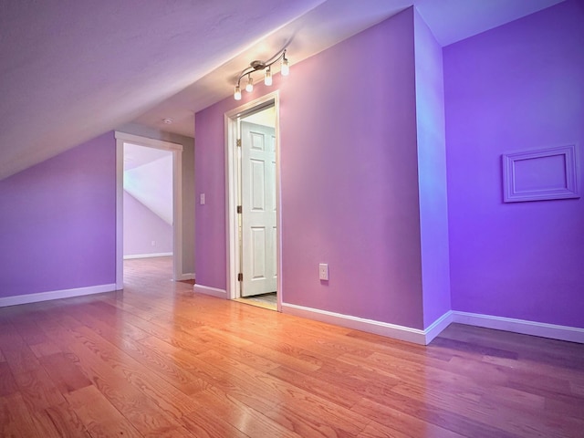 bonus room featuring lofted ceiling, light wood-type flooring, and baseboards