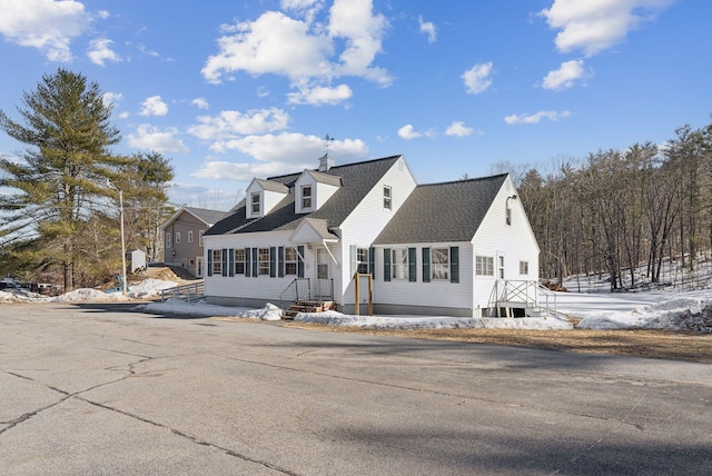 new england style home with roof with shingles