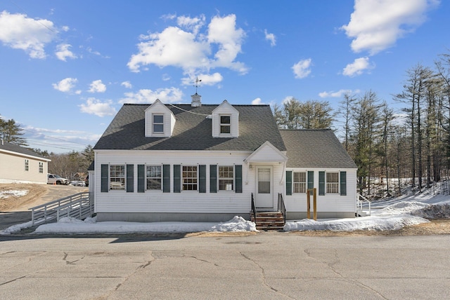 cape cod-style house with entry steps, a shingled roof, and fence