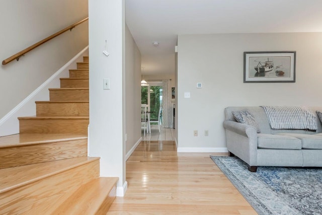 living room with stairway, baseboards, and light wood-style flooring