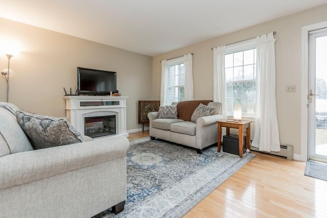 living area with wood finished floors, baseboards, a high end fireplace, and a baseboard radiator