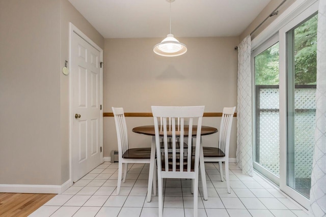 unfurnished dining area featuring a baseboard radiator, baseboards, and tile patterned flooring