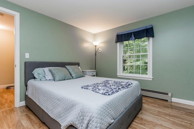 bedroom featuring baseboards, baseboard heating, and wood finished floors