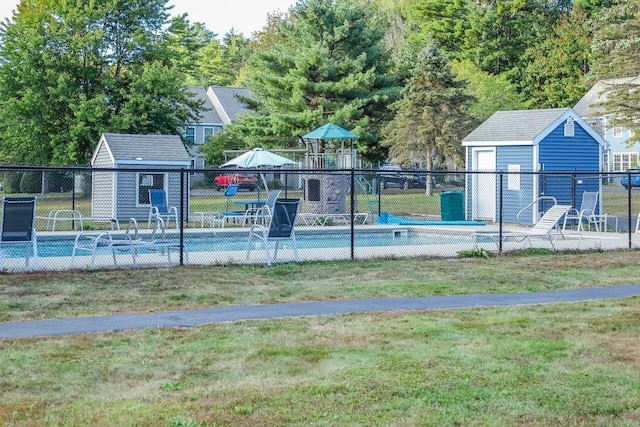 view of pool featuring an outbuilding, a lawn, a storage shed, and fence