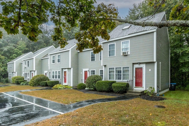 view of front of home with entry steps, a front lawn, and uncovered parking