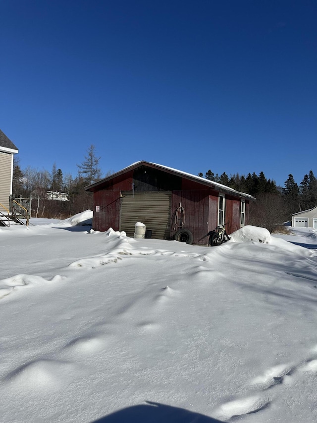 view of snow covered exterior with a garage and an outbuilding