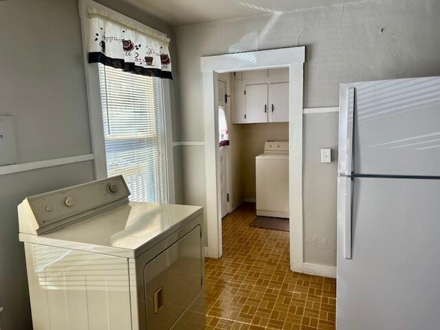 washroom featuring washer / dryer, cabinet space, and brick patterned floor