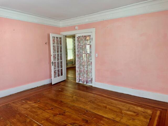 unfurnished room with hardwood / wood-style floors, crown molding, and baseboards