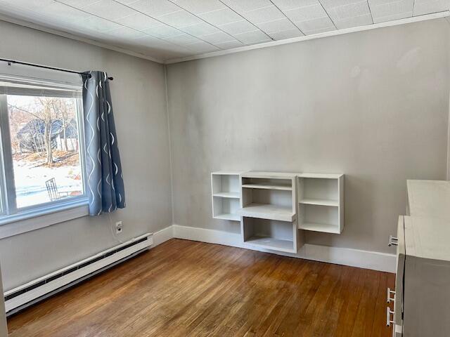 interior space with a baseboard heating unit, baseboards, and dark wood-type flooring