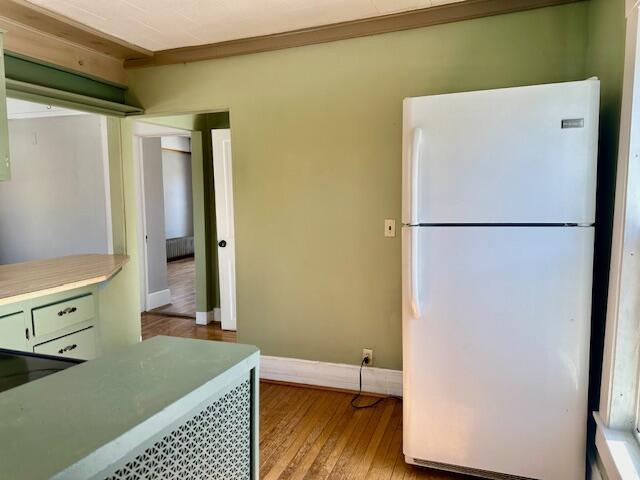 kitchen featuring light countertops, freestanding refrigerator, baseboards, and wood-type flooring