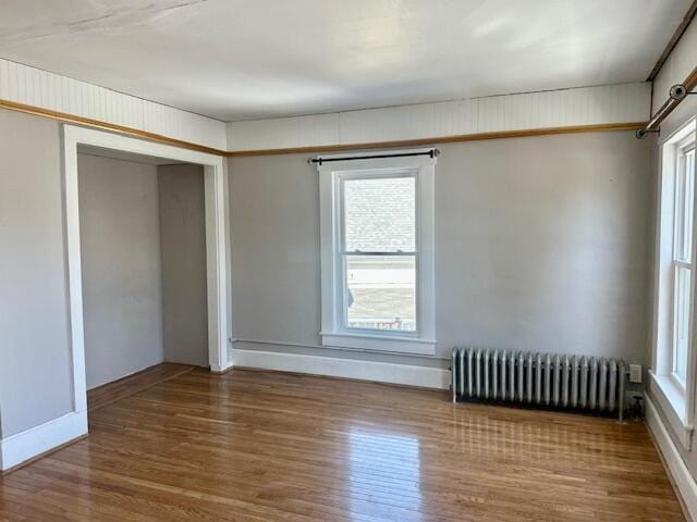 interior space featuring radiator heating unit, wood finished floors, a closet, and baseboards