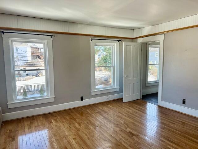 empty room featuring baseboards, plenty of natural light, and hardwood / wood-style flooring