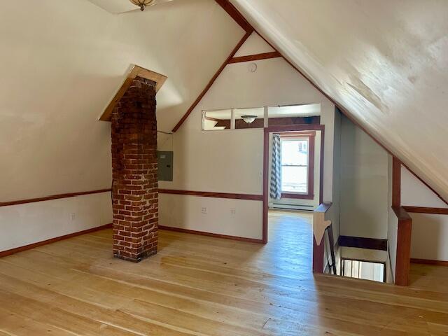 bonus room featuring a baseboard radiator, baseboards, lofted ceiling, and wood-type flooring