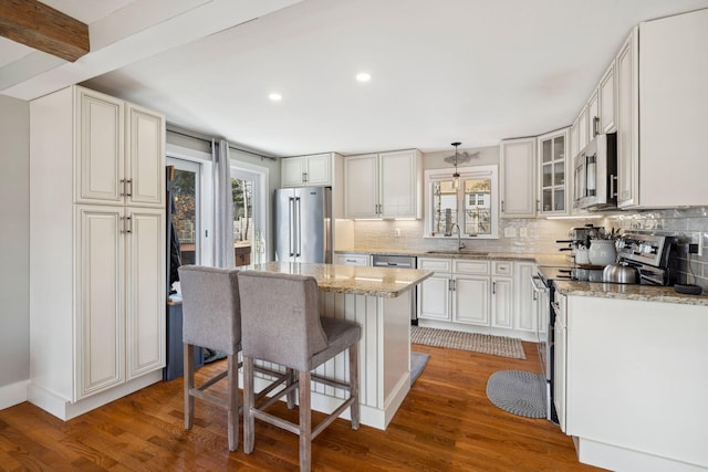 kitchen featuring wood finished floors, backsplash, stainless steel appliances, and a sink