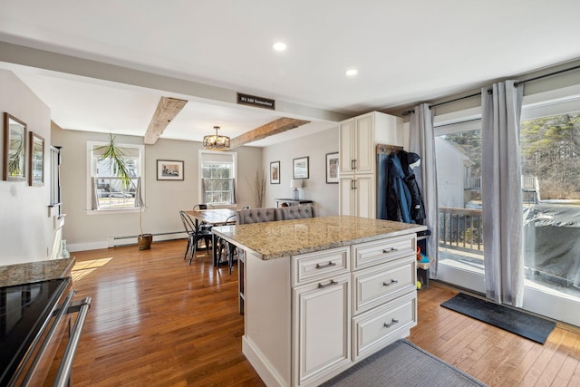 kitchen with stainless steel electric stove, wood-type flooring, white cabinets, light stone countertops, and baseboard heating