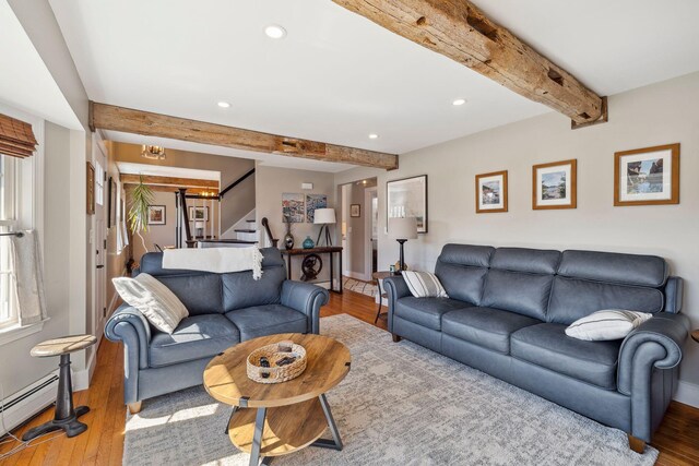 living area featuring beam ceiling, stairway, and wood finished floors